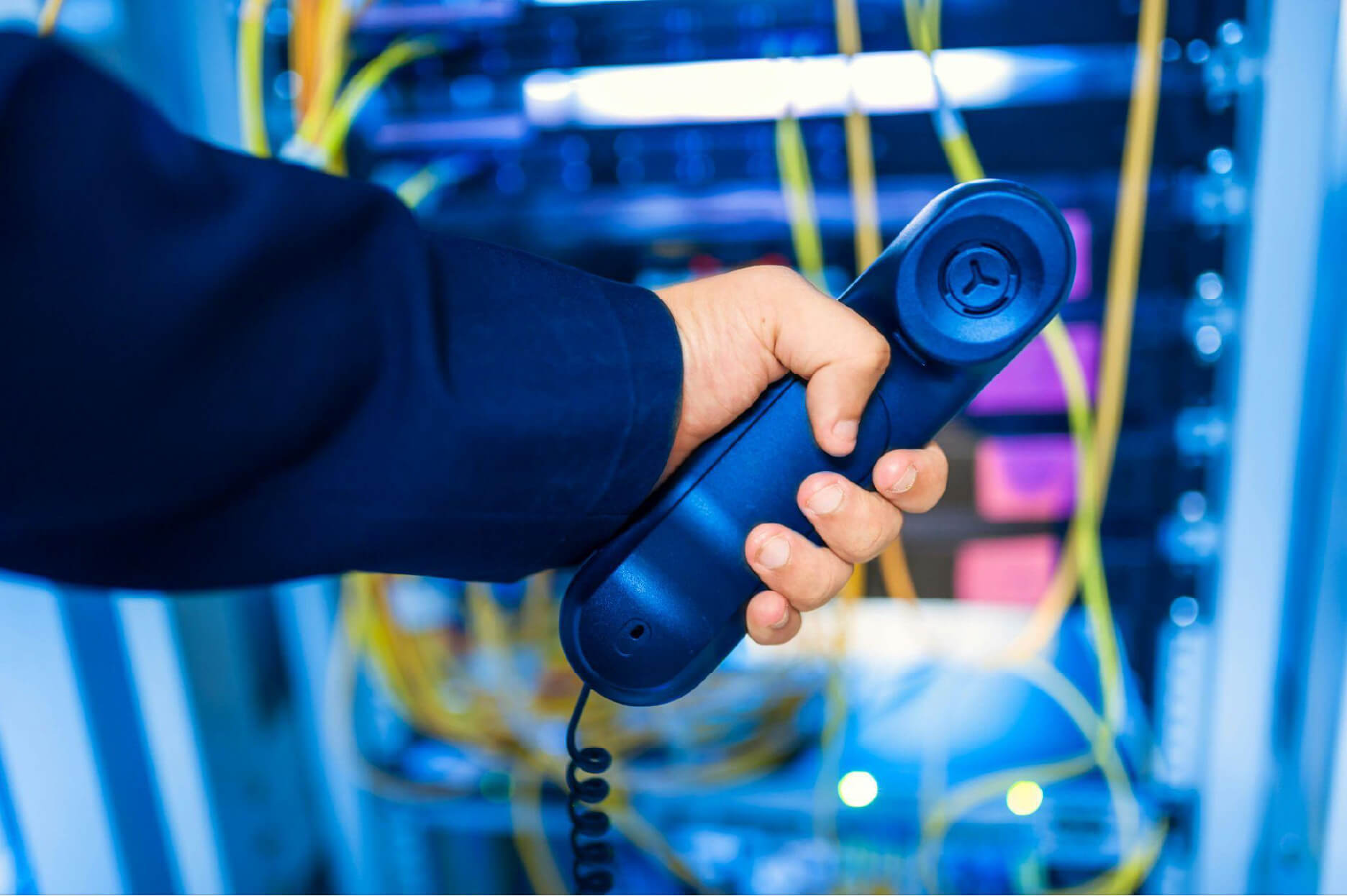 A person holds the receiver while looking through the VoIP wires.
